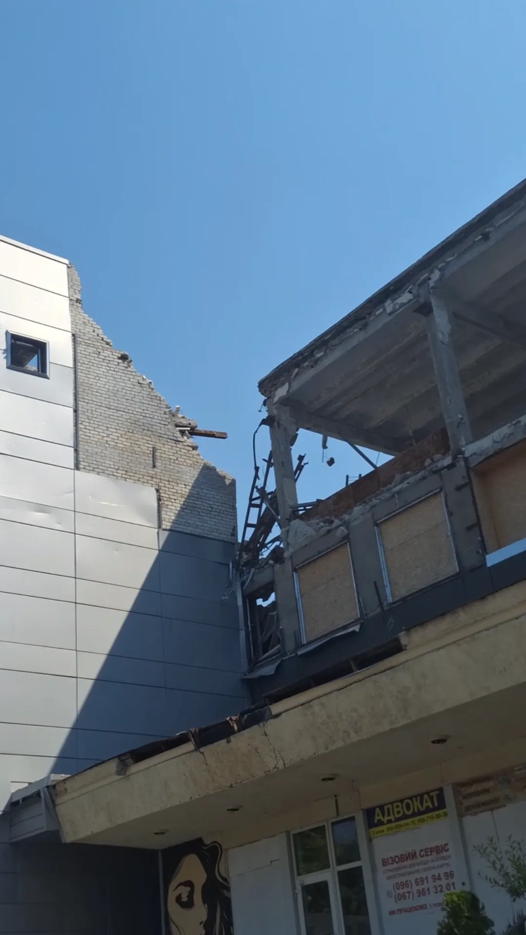 A damaged multistory building in Zaporizhzhia has exposed walls, beams, and missing sections of its interior.