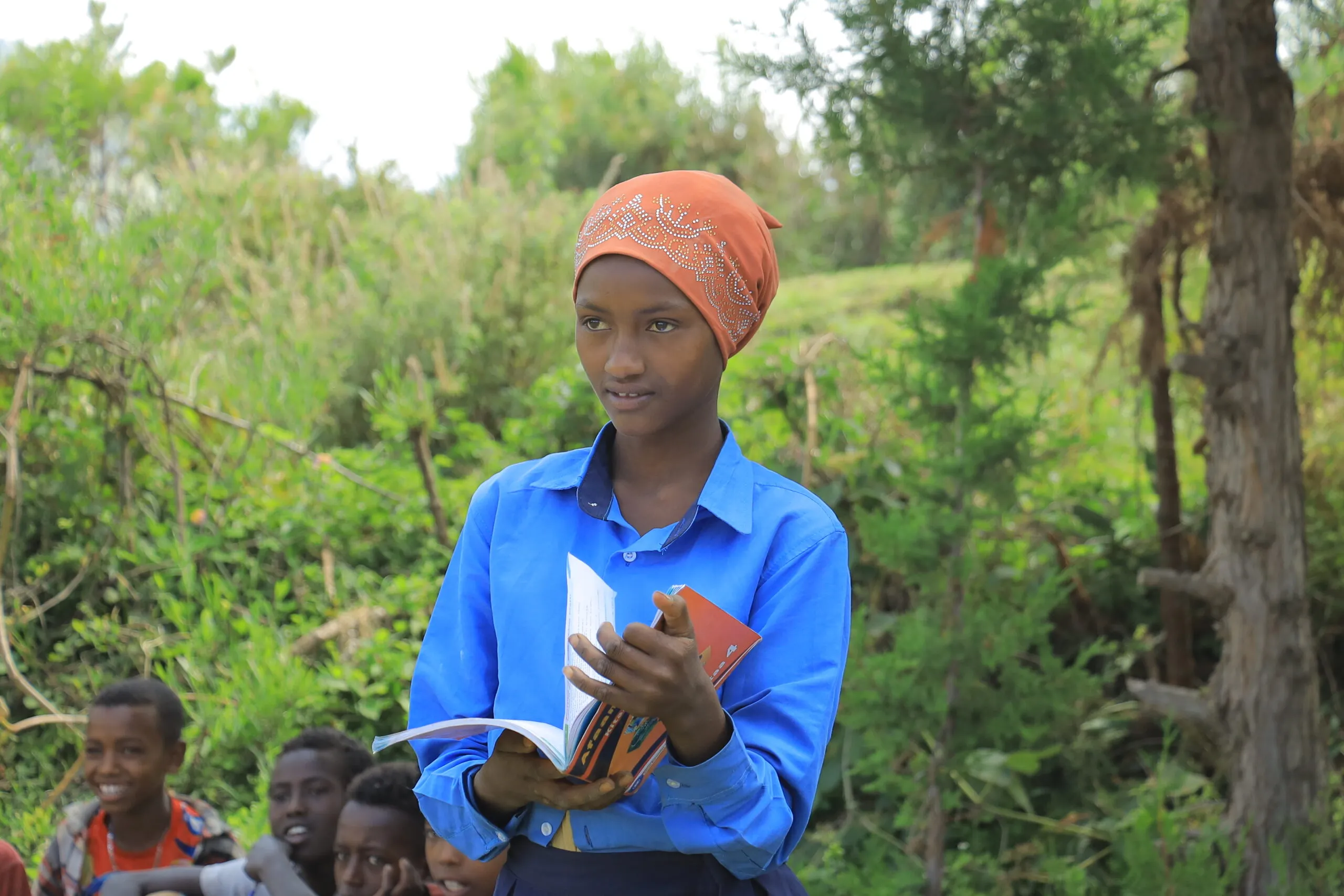A young woman standing outside with a book.