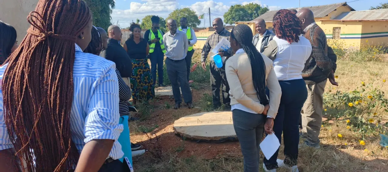 A group of people visiting a WASH program in the field.
