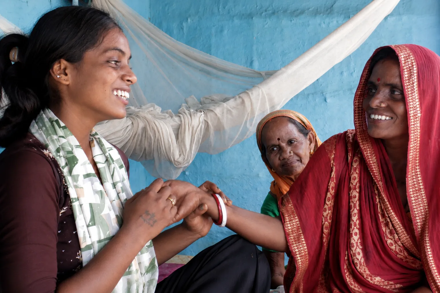 A young woman shares a laugh with two other women.