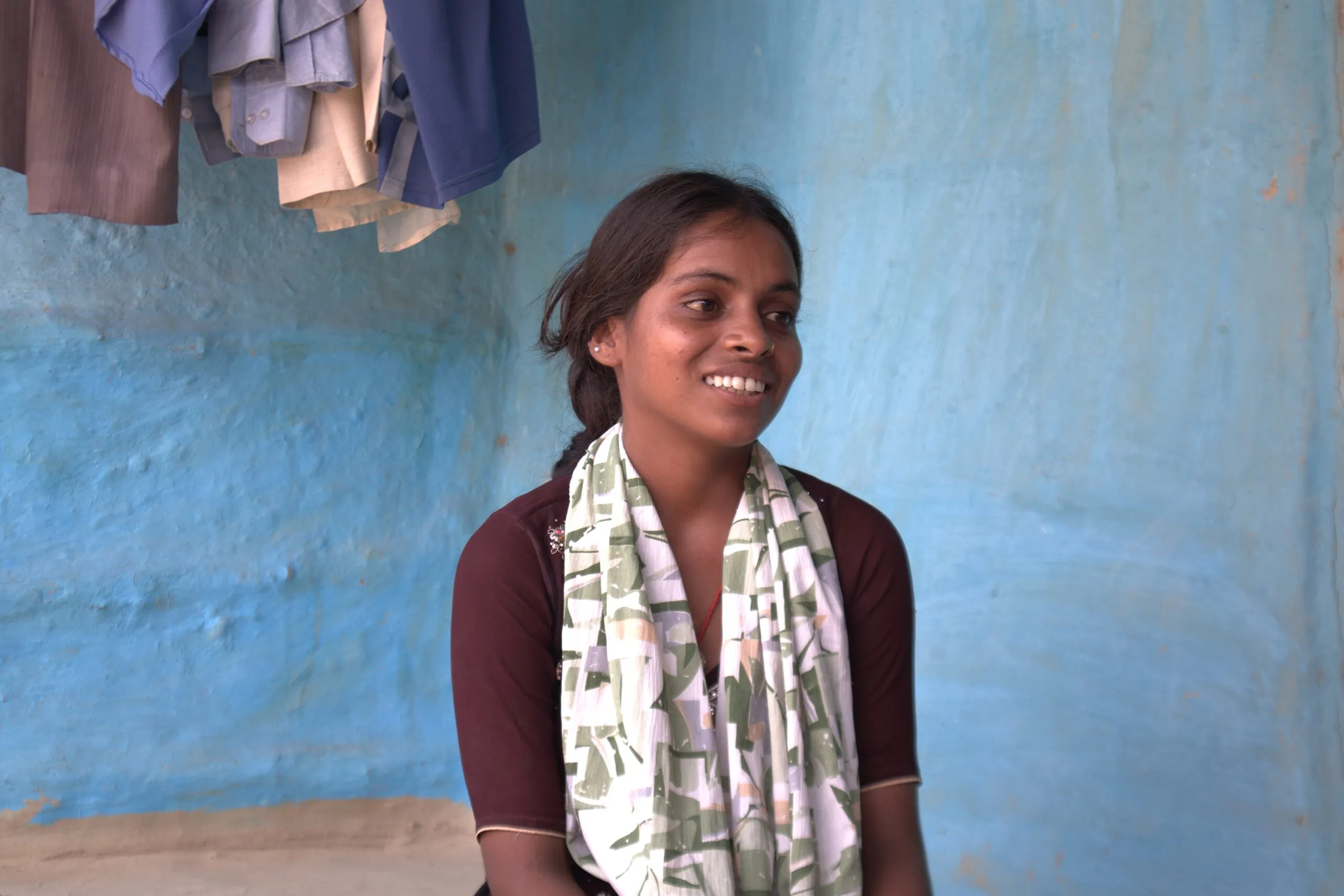 A young woman smiling with blue walls behind her.