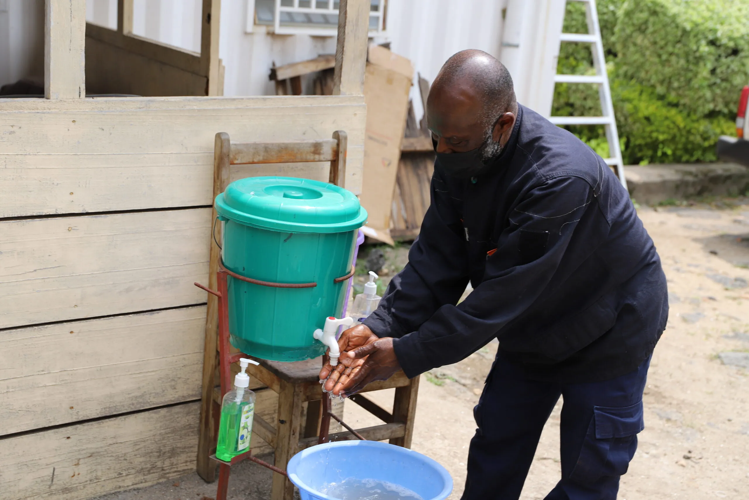 A man washing his hands at an outside handwashing station.