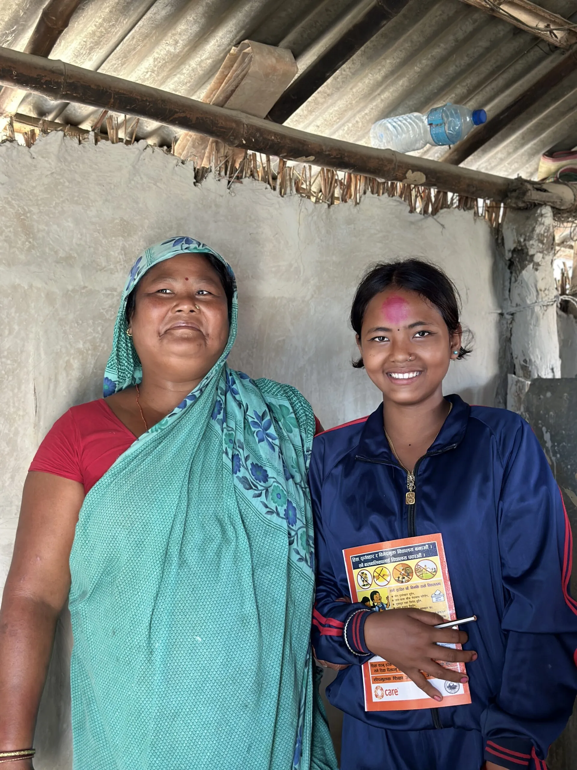 A mother and daughter standing next to each other and smiling.